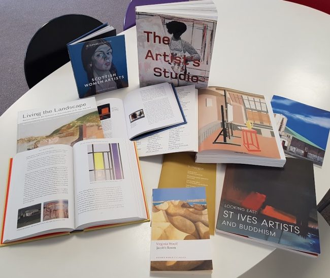 A selection of books on a table, some stood up, some open, some closed