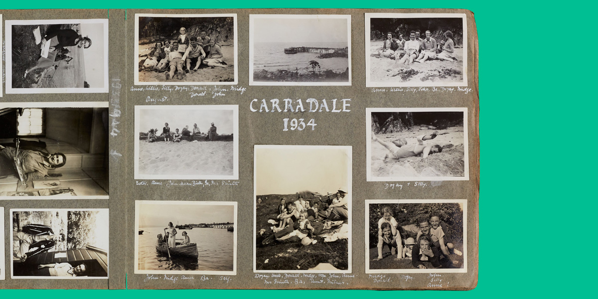 page of photo album with black and white images of groups of people sat together on a beach with 'Carradale 1934' written in white ink at the centre of the page