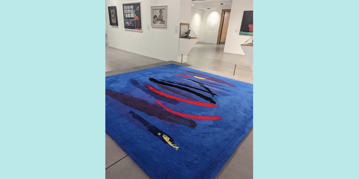 A colour photo of a blue rug on a gallery floor